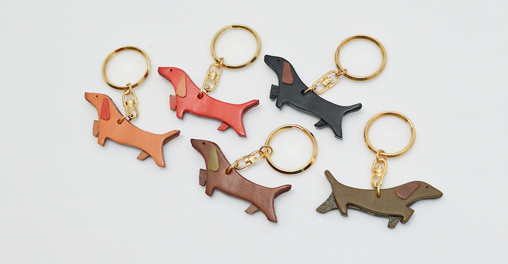 皮革製臘腸狗造型鑰匙圈，共五色：橘棕、紅色、黑色、深棕、橄欖綠，搭配金色鑰匙環。