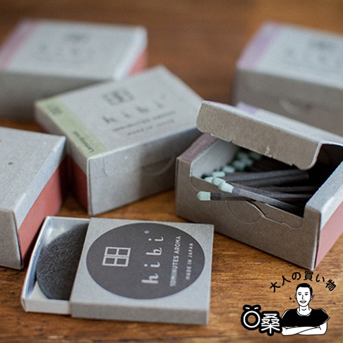 香氛火柴禮盒經典款(5入組)，灰褐色紙盒包裝，部分盒蓋打開，露出淺綠色火柴頭的深色火柴棒，散置於木質桌面。