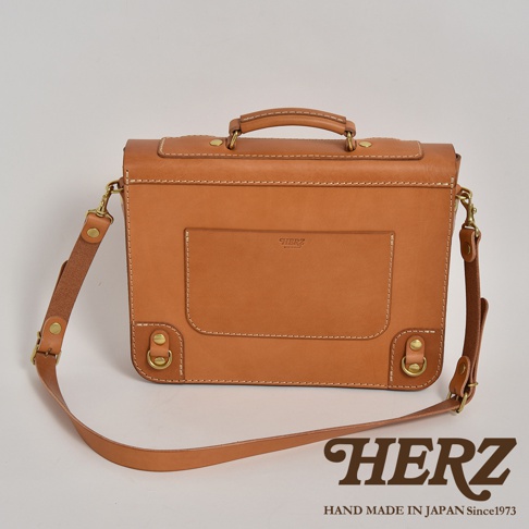 職人手作皮革歐風三用學生包，呈現自然棕色皮革，帶有精緻縫線與金屬扣環，可手提或肩背。