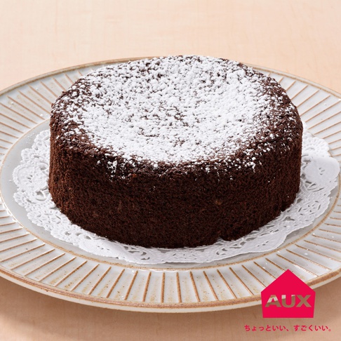 圓形巧克力蛋糕，表面撒滿白色糖粉，置於白色蕾絲紙上，再放在淺盤中，盤邊有條紋裝飾。