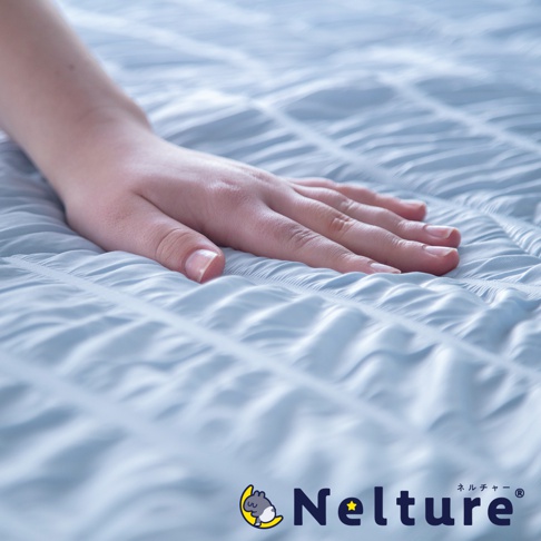 Nelture 涼爽夏夜舒眠單人被，淺藍色，織物表面有細緻的壓紋，呈現波浪狀的紋理，手部輕柔觸碰。