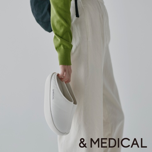 & MEDICAL 品牌標誌出現在白色拖鞋旁邊，展示者身穿綠色上衣和米白色褲子。