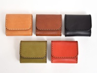 五個職人手作皮革雙折收納零錢包，分別為淺棕色、棕色、黑色、橄欖綠色和橘紅色，皆為皮革材質，以白色縫線裝飾邊緣。