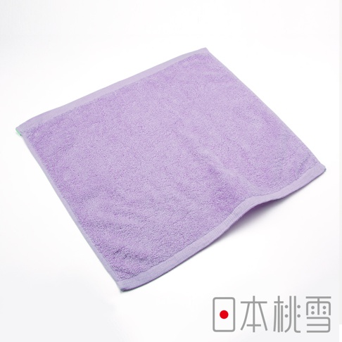 一條淺紫色毛圈毛巾，材質為棉，邊緣有細緻縫線，角落露出綠色標籤。