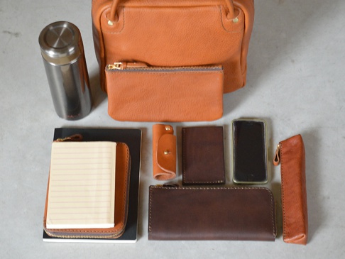 Mサイズ収納例:水筒、小物入れ・ポーチ(GS-2-M)、文庫本、ブックケース(GS-37-S)、A5ノート、ギボシ留め縦型キーケース(GS-23)、縦型パスケース(GS-24)、iPhone、ペンケース(GS-28-S)、ラウンドファスナー長財布(GS-27)