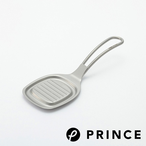 銀色金屬材質的小磨泥器，帶有橢圓形磨板，上面佈滿細小的磨孔。磨板連接到一個帶有弧度的雙柄手把。