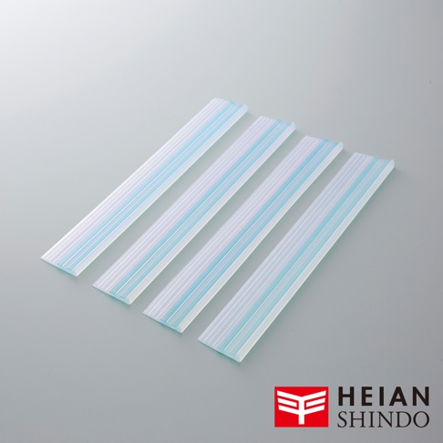 四條長條狀的家具防倒固定墊，為半透明白色，帶有淺藍色條紋，材質為橡膠或類似彈性材料。