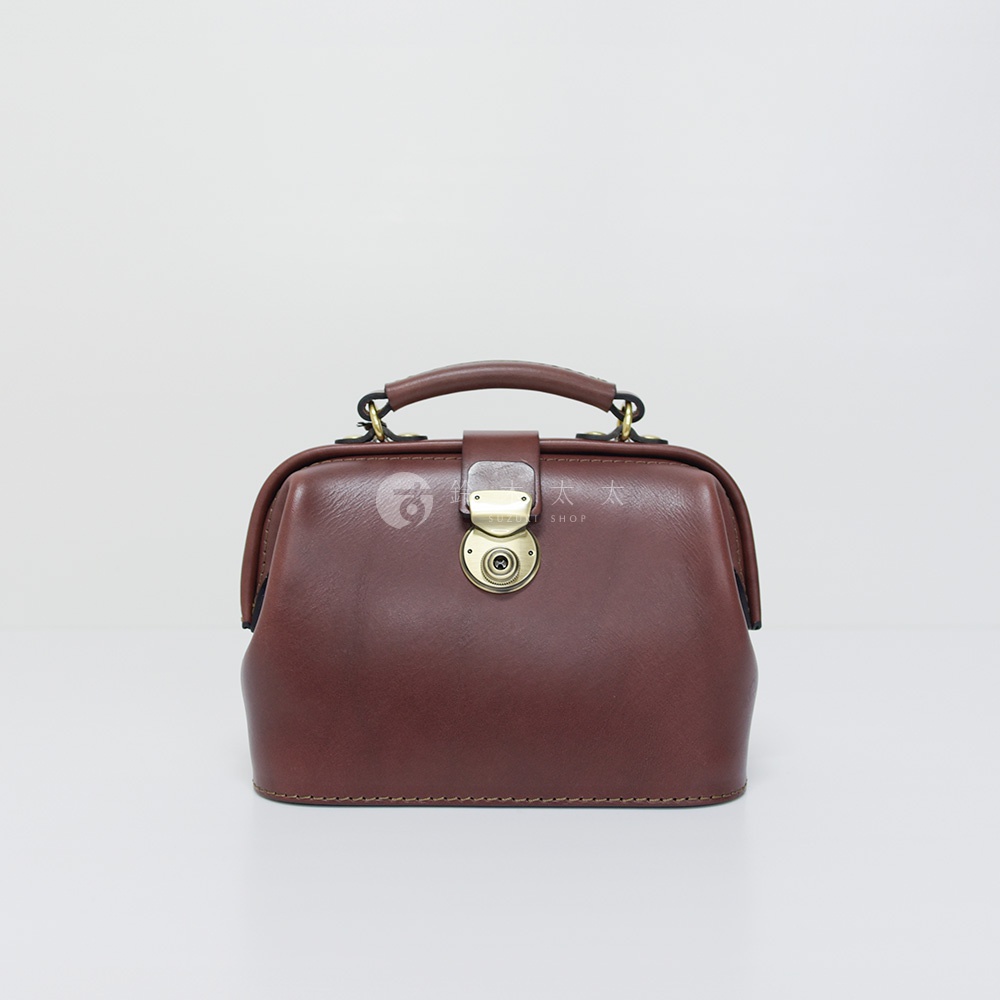 職人手作皮革方型迷你醫生包，採用深棕色皮革，配有金色旋轉鎖扣和提把。
