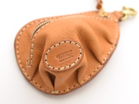 職人手作皮革餃子造型零錢包，採用天然棕色皮革，車縫線清晰，帶有品牌壓印「HERZ MADE IN JAPAN」字樣，搭配金色金屬拉鍊與掛鉤。