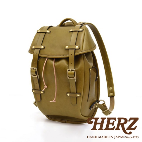 橄欖綠皮革經典雙扣後背包，配有兩條可調式肩帶、頂部提把、前袋及側袋。包身採用雙扣設計，並以粉色抽繩束口。