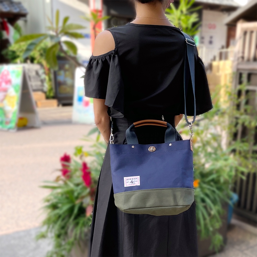 犬印純棉帆布兩用雙色托特包，深藍色包體搭配軍綠色底部，設有皮革提把和可拆卸肩背帶。