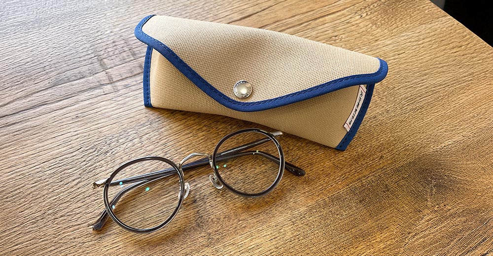 一個裝有眼鏡的帆布收納盒，放在木桌上