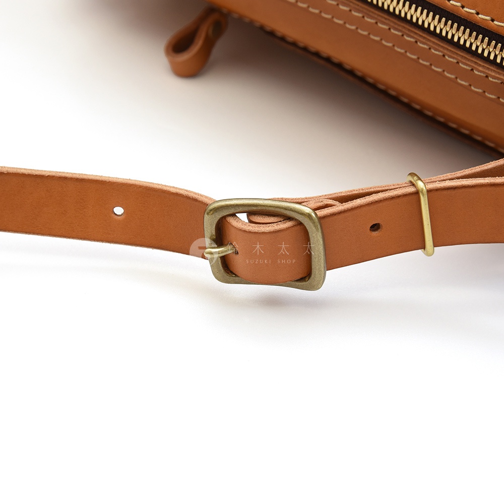 職人手作皮革長方型後背包 R-17，特寫展示淺棕色皮革材質的肩帶、金屬扣環及調節環，細膩車縫線清晰可見。