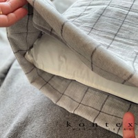 GRAPH 草木染格紋有機棉枕套，淺灰色調，帶有深灰色細緻格紋，材質為有機棉，觸感柔軟，部分露出白色枕芯。