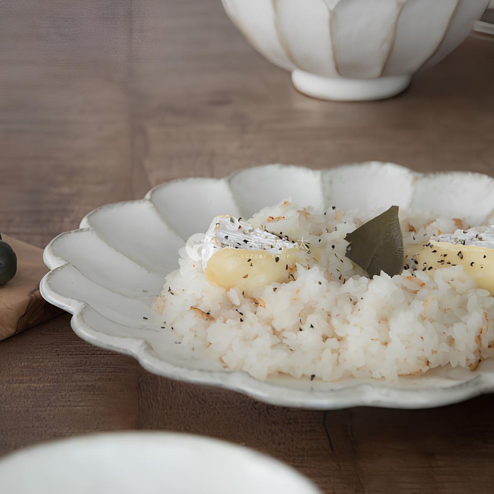 白色陶製花型主食盤，盤緣有六瓣花型紋路，盤中盛有飯、起司塊與香料，整體呈現樸實的日式風格。
