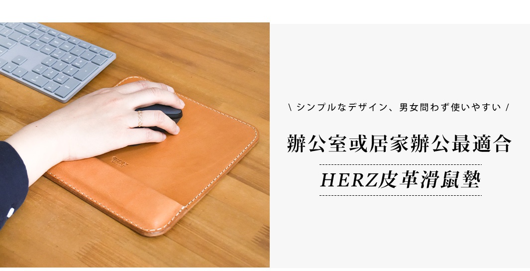 職人手作皮革滑鼠墊，採用天然皮革材質，呈現溫潤的棕色調，搭配細緻的車縫線。左側可見銀色鍵盤與無線滑鼠，右手使用者正操作滑鼠。