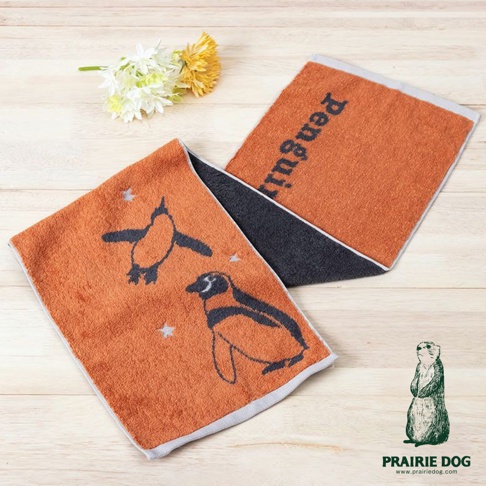 雙色運動毛巾，一面為橘色，繡有企鵝圖案與星星，另一面為深灰色，印有「Penguin」字樣。