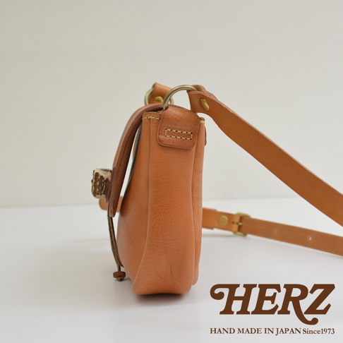 職人手作皮革鹿角扣繩肩背包，展示淺棕色皮革，設有鹿角形狀的扣環和可調節的皮革背帶，側面視角。