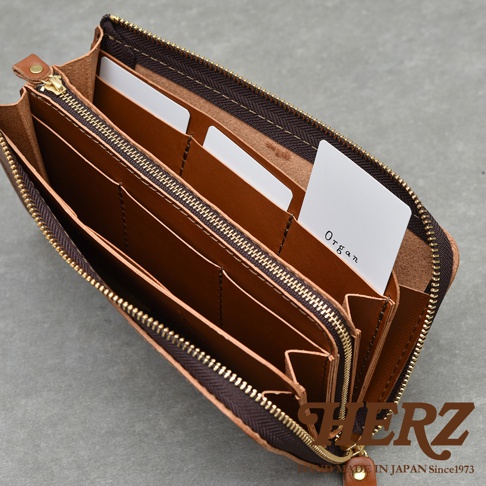 多隔層設計的棕色皮革長夾，內部有數個卡槽和夾層，拉鍊閉合，右下角有品牌標誌HERZ，下方有MADE IN JAPAN Since1973字樣