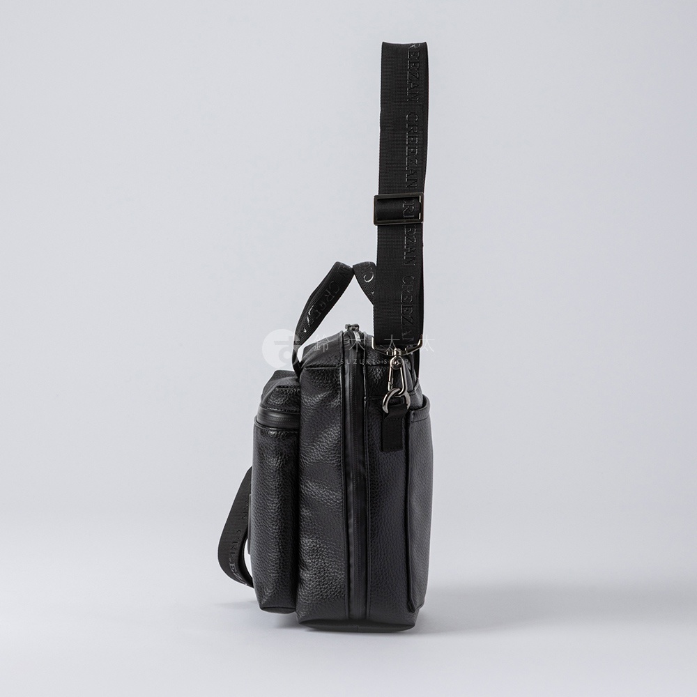 黑色皮革方形側背包，有拉鍊主隔層、前置口袋和可調式肩帶，肩帶上有品牌文字。