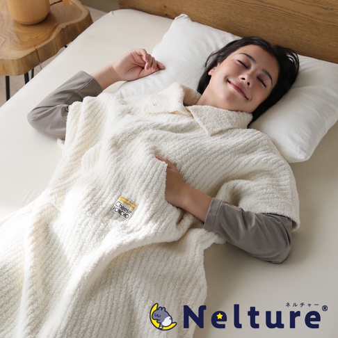 一位女子穿著白色起司斗篷，仰躺在床上，閉眼微笑，斗篷上有「CHEESE PONCHO」的標誌，下方有 Nelture 品牌標誌。