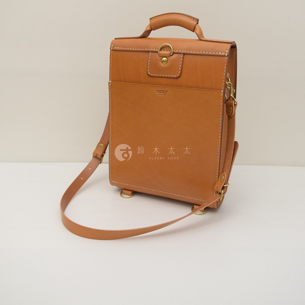 職人手作復古皮革後背包，採用溫潤的棕褐色皮革，設有前置收納袋、金屬扣環及可調節的肩帶，展現經典工藝。