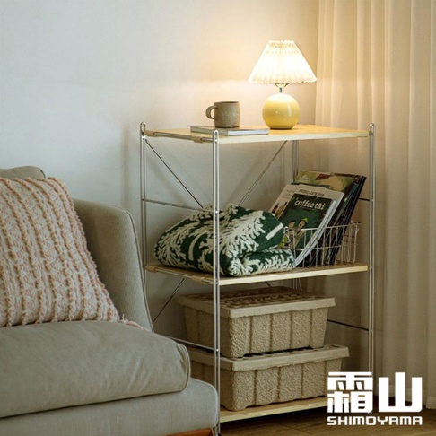 60公分寬的不鏽鋼三層收納置物架，置物架上有黃色檯燈、馬克杯、書籍、綠色圖案毛毯和兩個米色收納盒。