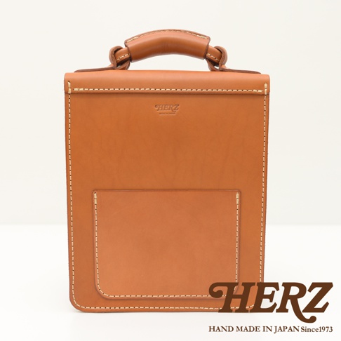 職人手作淺棕色皮革單肩兩用小方包，簡約設計，搭配頂部提把與正面方形口袋，車線精緻，展現皮革質感。