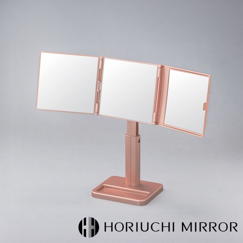 玫瑰金色的 NAPURE 桌上型三折化妝鏡，由三片方形鏡面組成，可旋轉調整角度，鏡架為金屬材質，帶有可調節高度的支架和方形底座。