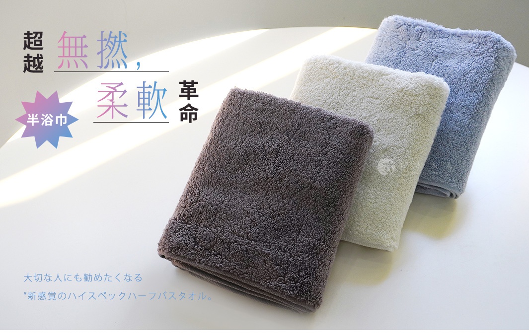 三條不同顏色的毛巾，由深棕色、米白色和淺藍色組成，堆疊擺放，並有日文和中文的標語。