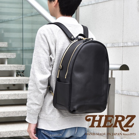 黑色皮革多功能後背包，附有金色拉鍊和側面口袋，由男性背著。