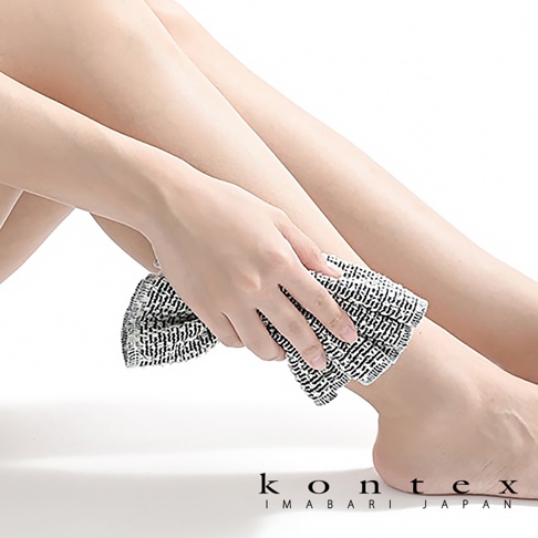 一只手拿著一條黑白條紋的按摩洗澡巾，輕輕擦拭著小腿。