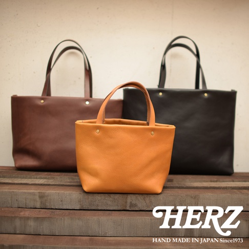 三款職人手作皮革托特包，分別為棕色、橘棕色和黑色，皆為極簡設計，配有皮革提把和金屬鉚釘，材質為真皮。