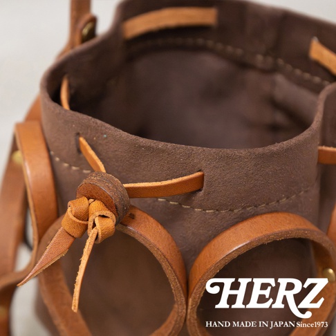 日本HERZ手工皮革編織水桶包，特寫頂部細節，標有HERZ品牌和手工製造字樣