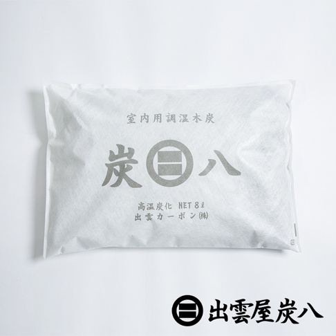 白色無紡布包裝著室內用調濕木炭，印有灰色「炭八」字樣和品牌標誌，包裝上標示「 NET 8L」、「高溫炭化」及「出雲碳(株)」。