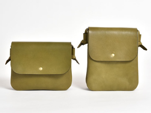 兩個橄欖綠色職人手作皮革隨行袋，一個橫式較寬，一個直式較長，皆有翻蓋及金色按扣設計。