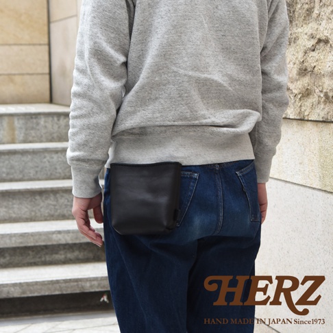 黑色皮革製多用途工作腰袋，附於牛仔褲腰部，呈現簡約設計。