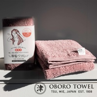 粉紅色毛巾，材質為棉，觸感柔軟，帶有細緻紋理。產品包裝上印有女性頭像圖案及日文說明，標示尺寸為 33x90 公分。