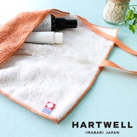 橙色毛巾收納袋內含一瓶黑色噴霧狀物、一條白色牙膏軟管，以及一支透明牙刷。收納袋邊緣為橙色滾邊，並配有兩條橙色細繩。