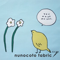 淺藍色帆布材質，左側有兩朵白色小花，花莖為綠色。右側有一隻黃色小鳥，頭頂上方有一個對話氣泡，氣泡內寫著「YOU MADE MY DAY.」，下方有「nunocoto fabric」字樣。