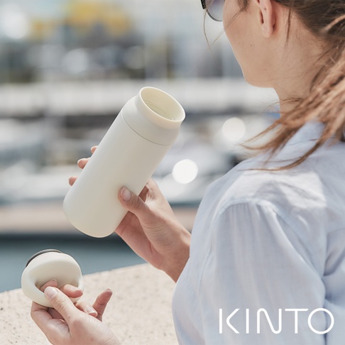 一位女性手持一個米白色、帶有瓶蓋的DAY OFF提式輕巧保溫瓶，瓶身為霧面金屬質感，瓶口內側為淺色。