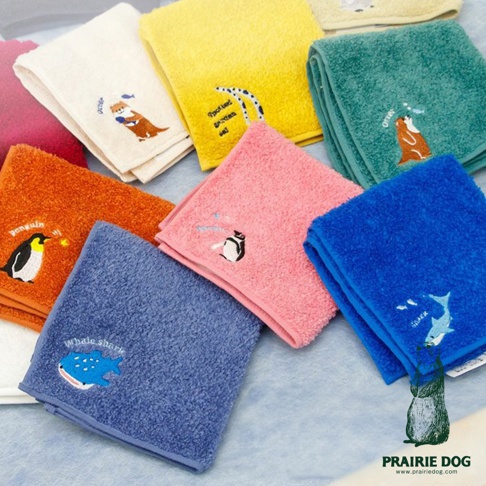 多款今治精梳棉方巾，材質柔軟，表面有動物刺繡圖案，包括企鵝、水獺、鯊魚等，顏色包含粉紅、黃色、橘色、藍色、綠色、白色及紅色。