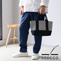 一手提著三河木綿刺子織OBI迷你托特包，包身採黑白格紋與黑色拼接設計，配有黑色提把。