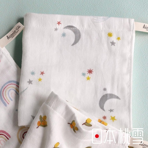 輕柔隨行快乾紗布方巾，印有月亮、星星及彩虹圖案，左上角有hiorie made in Japan品牌標籤，右下角有日本桃雪字樣