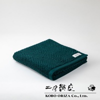 一條深綠色、觸感柔軟的有機棉浴巾，表面織有明顯的人字紋路，角落縫有白色品牌標籤。