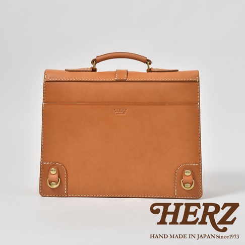 職人手作皮革三用單扣商務後背包，淺棕色，正面有品牌燙金標誌，單扣開合設計，附提把及兩側金屬D型環。