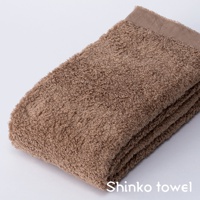 MAISON BLANC 輕奢柔膚匹馬棉浴巾，呈現溫暖的棕褐色，質地蓬鬆柔軟，邊緣有細緻的織紋。