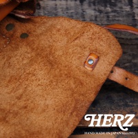 復古棕色皮革水洗加工，細膩絨面，帶有金屬釦和皮革束帶，展現職人手作質感。