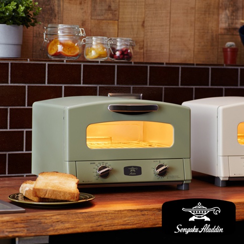 復古風格的綠色烤箱，配有透明視窗，內部燈光明亮，前方有兩個旋鈕，烤箱旁有兩片烤好的吐司。