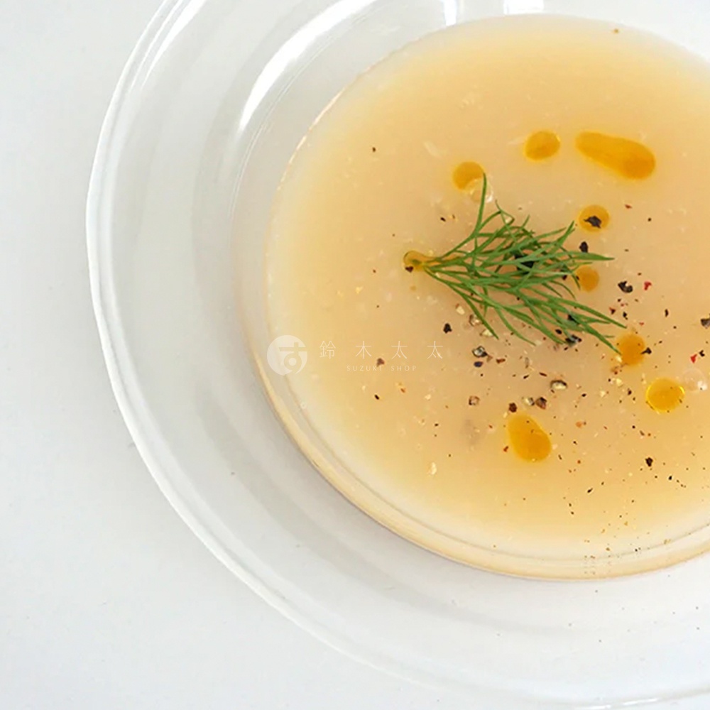 lykke 清透玻璃深型點心碗，盛有淡黃色湯品，表面撒有黑胡椒粒、香料及一小枝綠色香草，並淋上少許金黃色食用油。